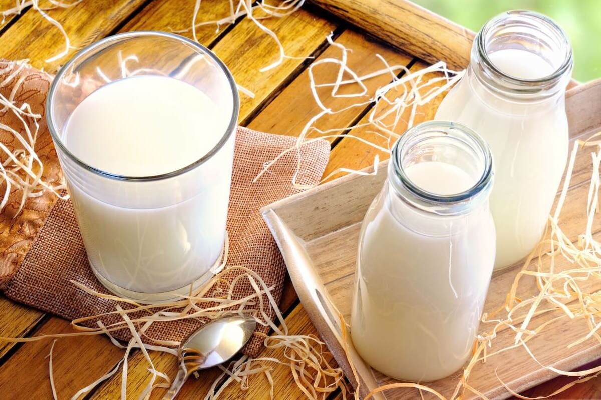 Two bottles and a glass of milk sit on a wooden table.