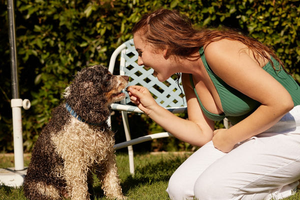 A woman holds a treat for her dog.