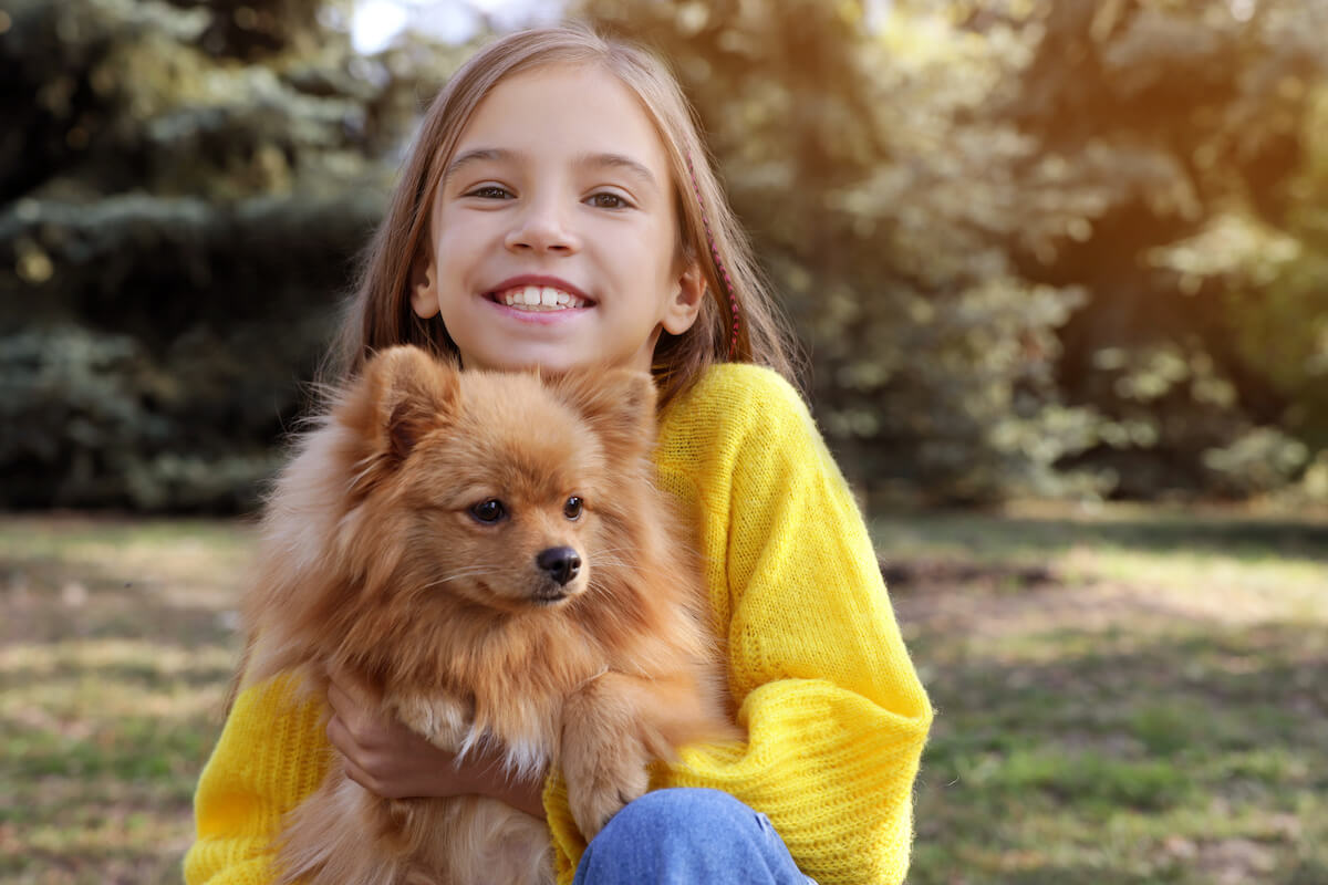 Are Pomeranians good with kids: girl hugging her Pomeranian