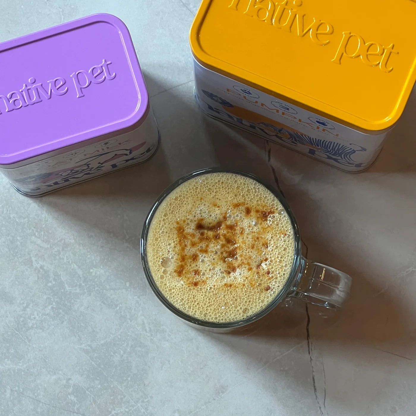 A frothy Pup-kin drink beside Native Pet Pumpkin and Goat Milk tins